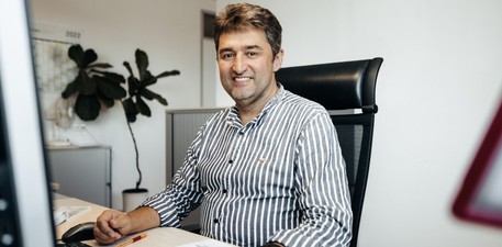 Mitarbeitende sitzt an einem Schreibtisch, schaut auf den Computer und telefoniert